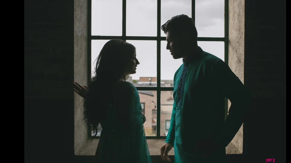 Paar in traditioneller Kleidung als Silhouette vor einem großen Fenster